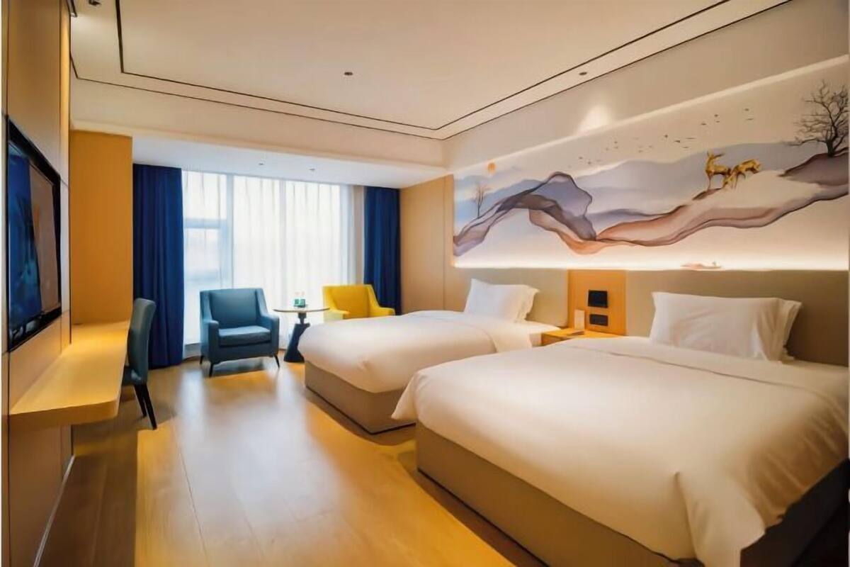 Een hotelkamer met twee bedden, een televisie, een bureau en een stoel.