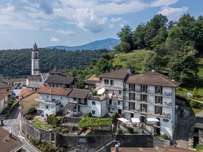 A town with a prominent tower, terraced houses, and a hillside. - Guest House Giulietta e Romeo (Cossogno)