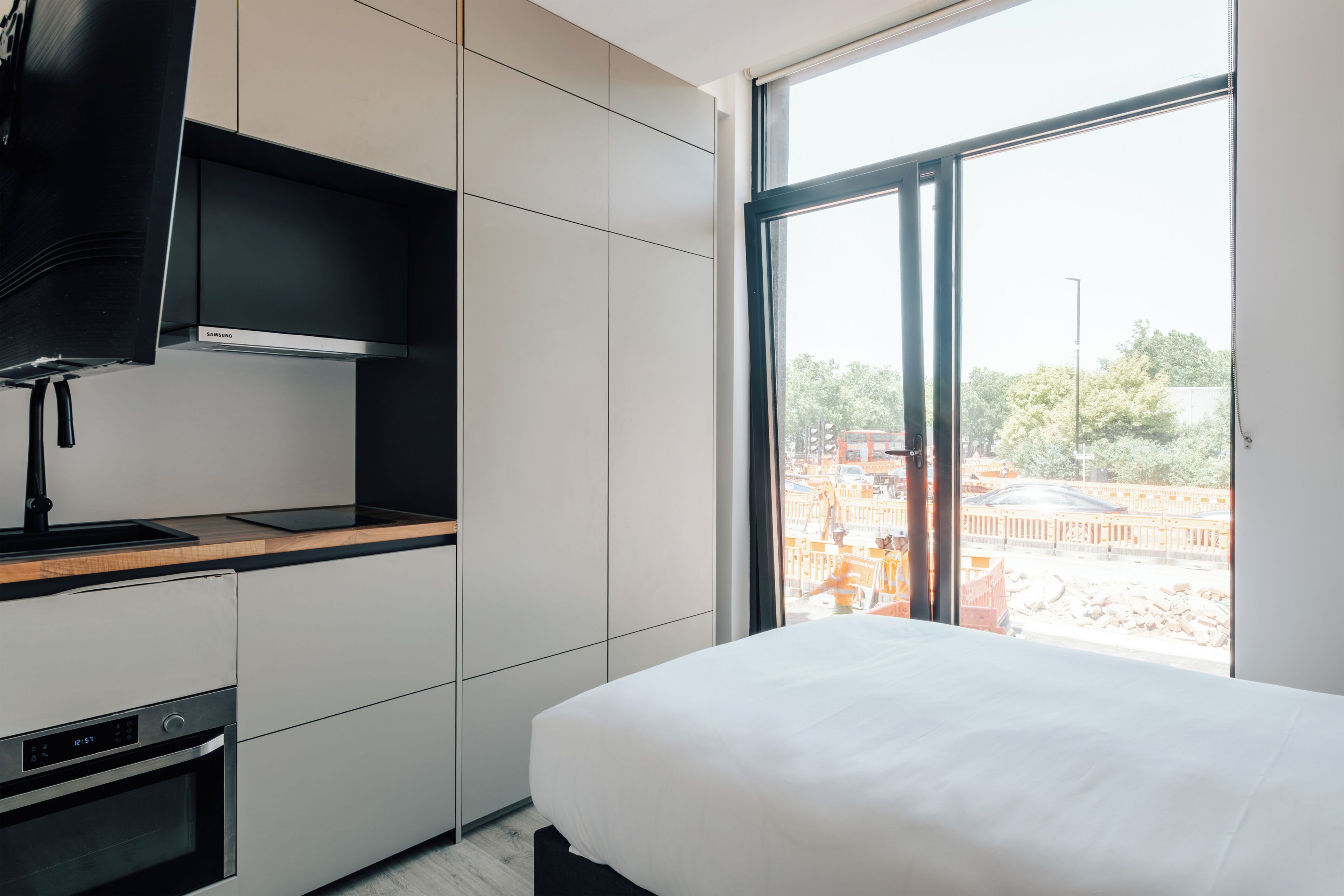 Et moderne hotelværelse med seng, indbygget fjernsyn og stort vindue med udsigt.