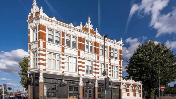 A historic building with a classic architectural style, featuring a prominent entrance with large glass doors and a detailed facade. - The Antigallican by Nestor (London)