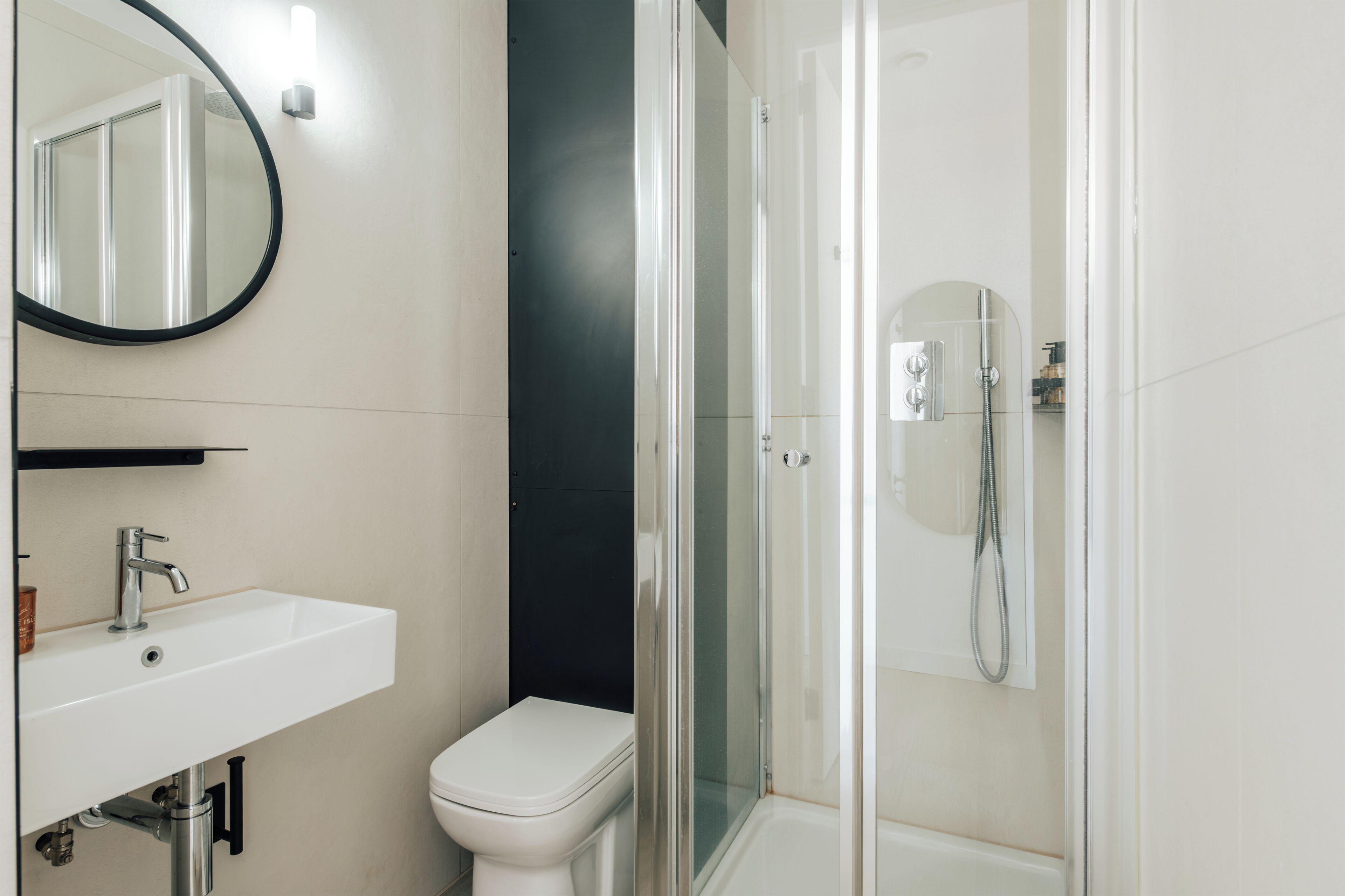 Un bany amb un lavabo blanc, vàter i dutxa amb envà.