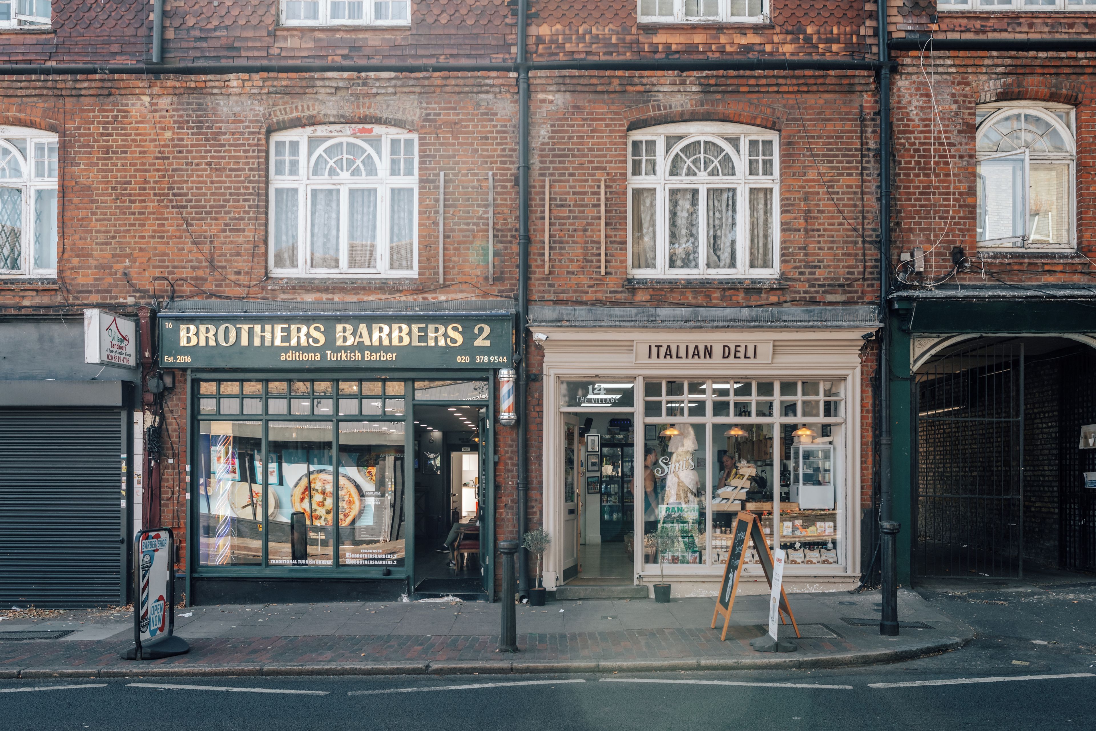 A street view with two storefronts: Brothers Barbers and Italian Deli.