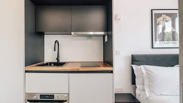 A compact kitchenette with a stainless steel oven, a sink, and a microwave.