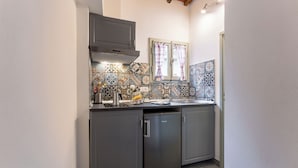 Cozinha compacta com armários cinza, lava-louças embutida e painel de azulejos com diversos padrões.