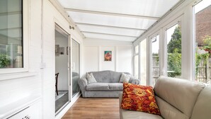 Une pièce baignée de lumière, avec un canapé gris, un canapé beige et un coussin décoratif à motifs.