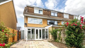 Un immeuble résidentiel de deux étages doté d’un patio, d’une clôture en bois et de plantes à fleurs.