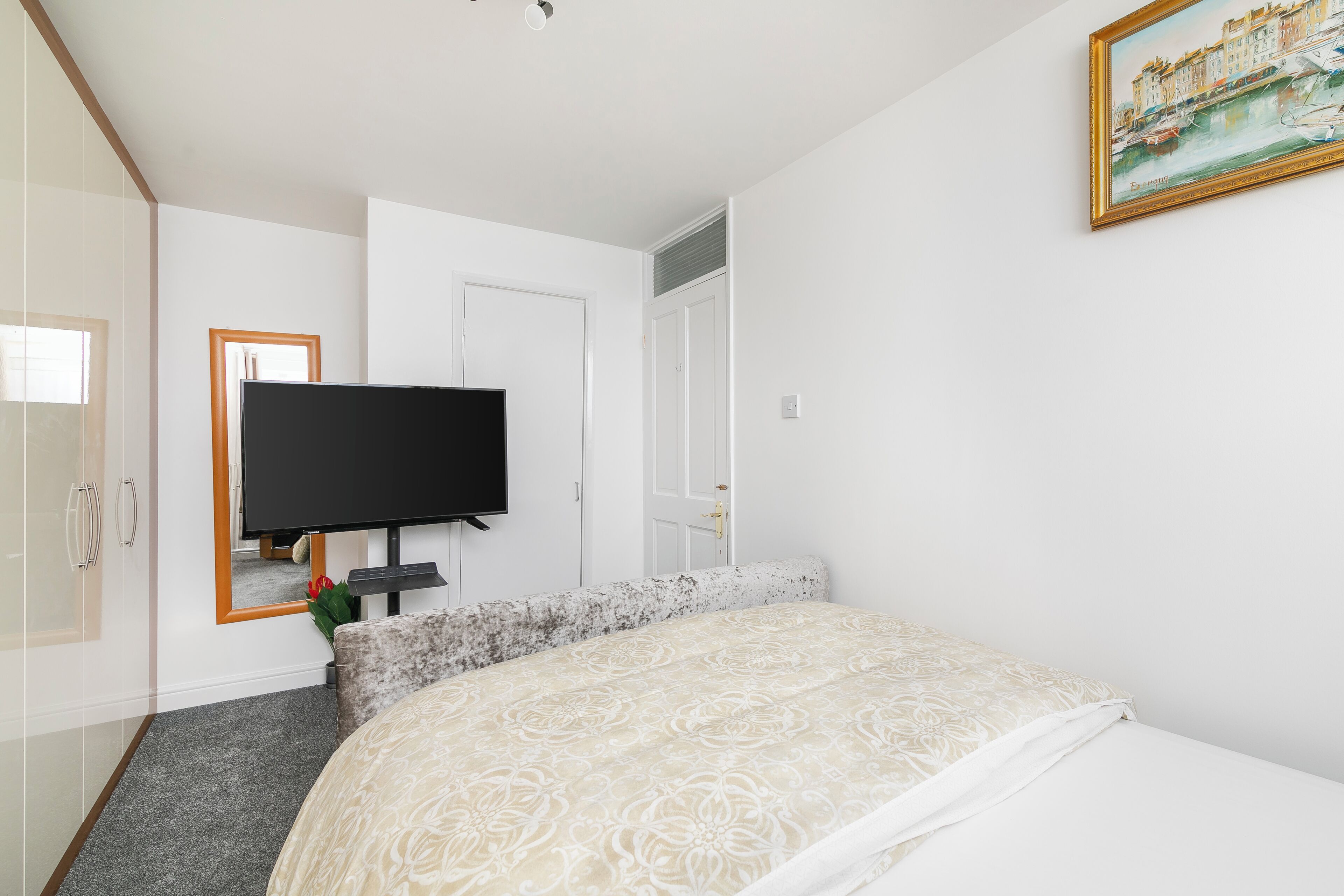 Una habitación de hotel con una cama, televisión, armario y un cuadro en la pared.