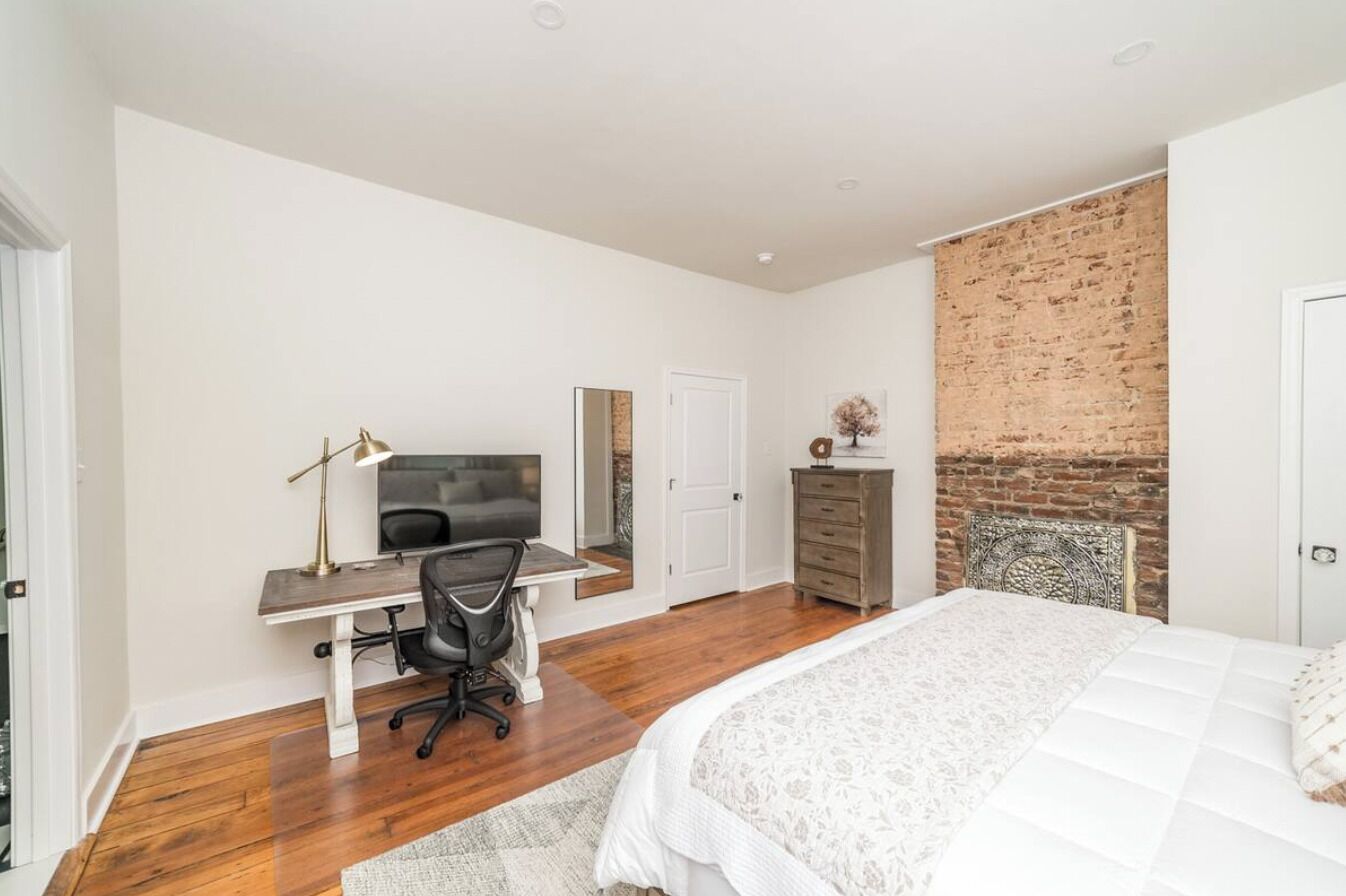 Une chambre à coucher avec un lit, un bureau, une chaise, une télévision et un mur en briques.