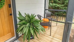 A wooden deck with a potted fern and a chair.