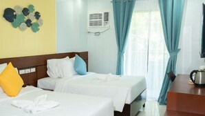 A hotel room with two beds, a desk, a coffee maker, and a wall-mounted air conditioner. - Bloom Boracay (Boracay Island)