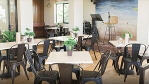 A dining area with tables and chairs, potted plants, and a mural on the wall. - Bloom Boracay (Boracay Island)