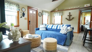 Un salon chaleureux avec un canapé bleu, des poufs en osier et une décoration d’inspiration marine.