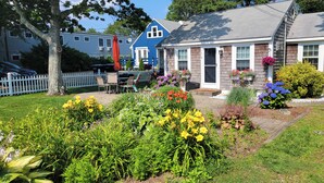 Une maison avec un jardin devant, une terrasse avec des chaises et une boîte aux lettres.