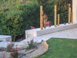 A garden with a concrete pathway, a small seating area, and bamboo poles. - Summer Home of Skaleta beach (9JP7+RM9 Skaleta)