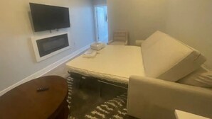 Une chambre d’hôtel avec un lit, un téléviseur fixé au mur, une table de chevet et une petite fenêtre.