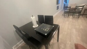 Un coin repas avec une table noire, quatre chaises et un porte-rouleau en papier blanc.