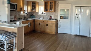 A modern kitchen with wooden cabinets, a white refrigerator, and a built-in stove. - Enjoy views of beautiful Houghton Lake in charming LARGE home that sleeps 10.  (Houghton Lake)