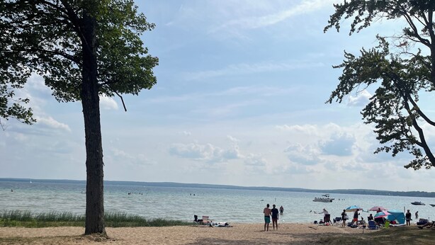 A beach with people, boats, and a clear sky. - Enjoy views of beautiful Houghton Lake in charming LARGE home that sleeps 10.  (Houghton Lake)