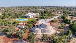 Une villa moderne dotée d’une piscine, de structures en pierre et d’un jardin luxuriant.