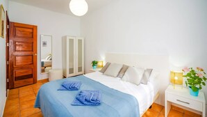 A bedroom with a bed, a wardrobe, a bedside table, a lamp, and a potted plant. - Villa Arisen by Villa Plus (Playa Blanca)