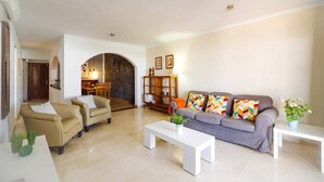 A spacious living room with a sofa, armchairs, and a coffee table. There is a dining area with a table and chairs in the background. - Villa Arisen by Villa Plus (Playa Blanca)