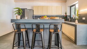Een moderne keuken met een centraal eiland, vier barstoelen en een raam dat voor natuurlijk licht zorgt.