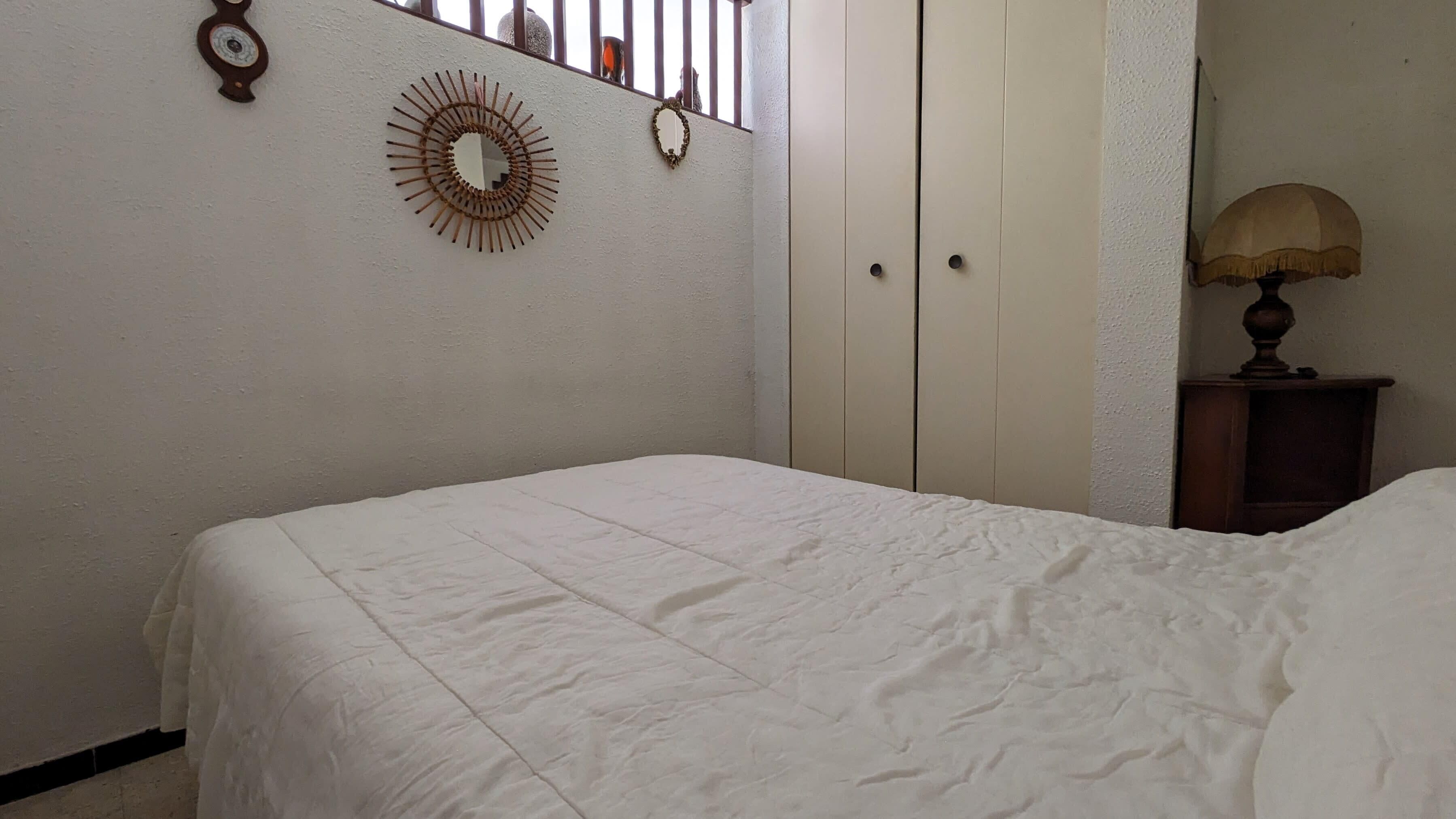 Une chambre à coucher avec un lit, une armoire, un miroir et une lampe.