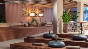 Un vestíbulo moderno con un mostrador de recepción de ladrillo, zona de estar y grandes plantas en macetas.