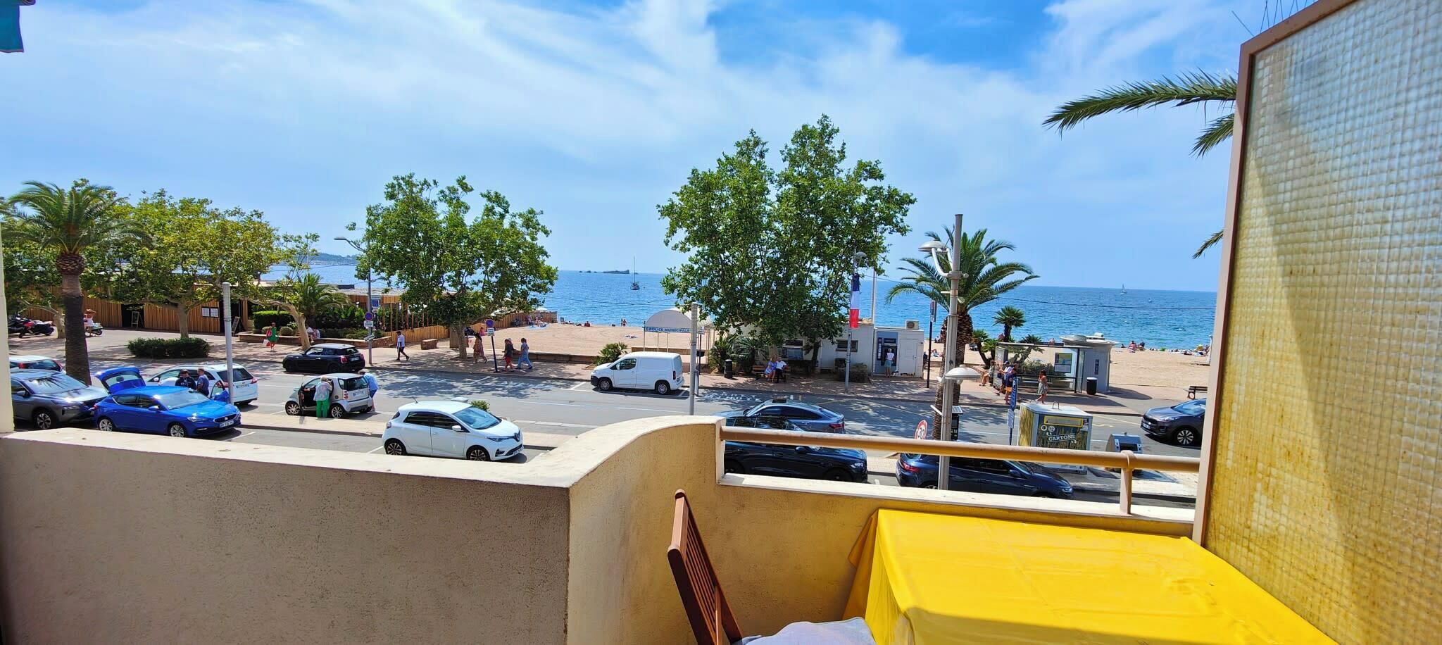 Ein Balkon mit Blick auf einen Strand, auf dem Autos geparkt und Palmen zu sehen sind.