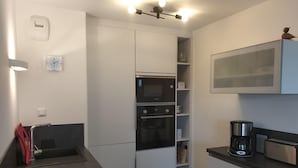 A compact kitchen with a microwave, oven, and coffee maker.