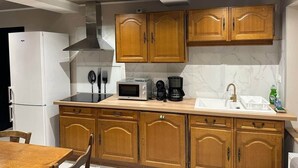 Una cocina con armarios de madera, un refrigerador blanco, un microondas, una cafetera y un lavamanos.