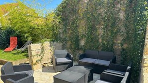 Un espacio al aire libre con mobiliario de mimbre, pared de piedra y una silla roja.