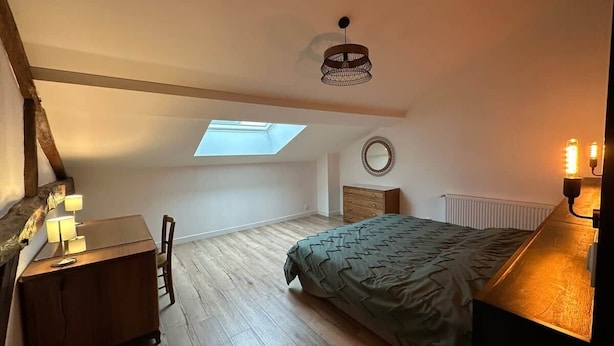 Un dormitorio con tragaluz, una cama, un escritorio y un aparador.