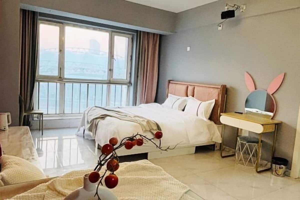 Un dormitorio con cama, escritorio, silla, ventana con cortinas y un adorno de pared.