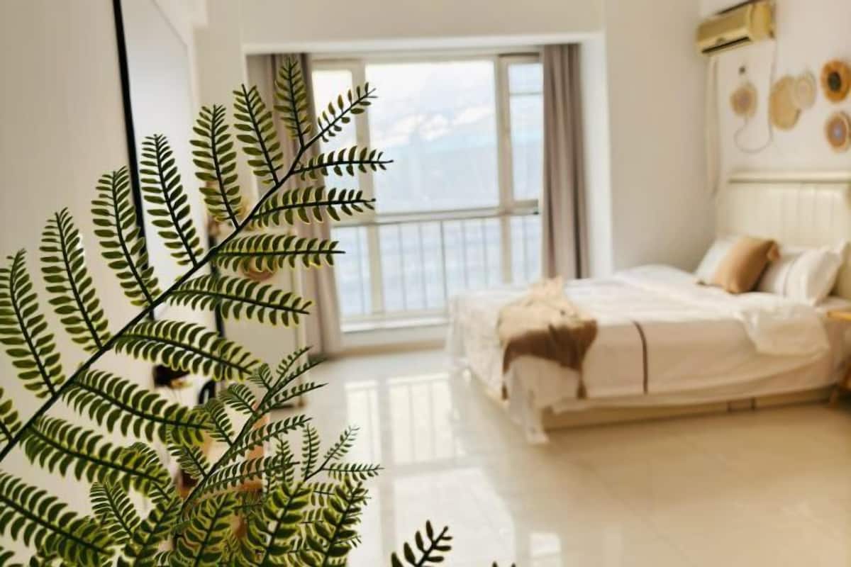 Un dormitorio con cama, ventana y una planta.