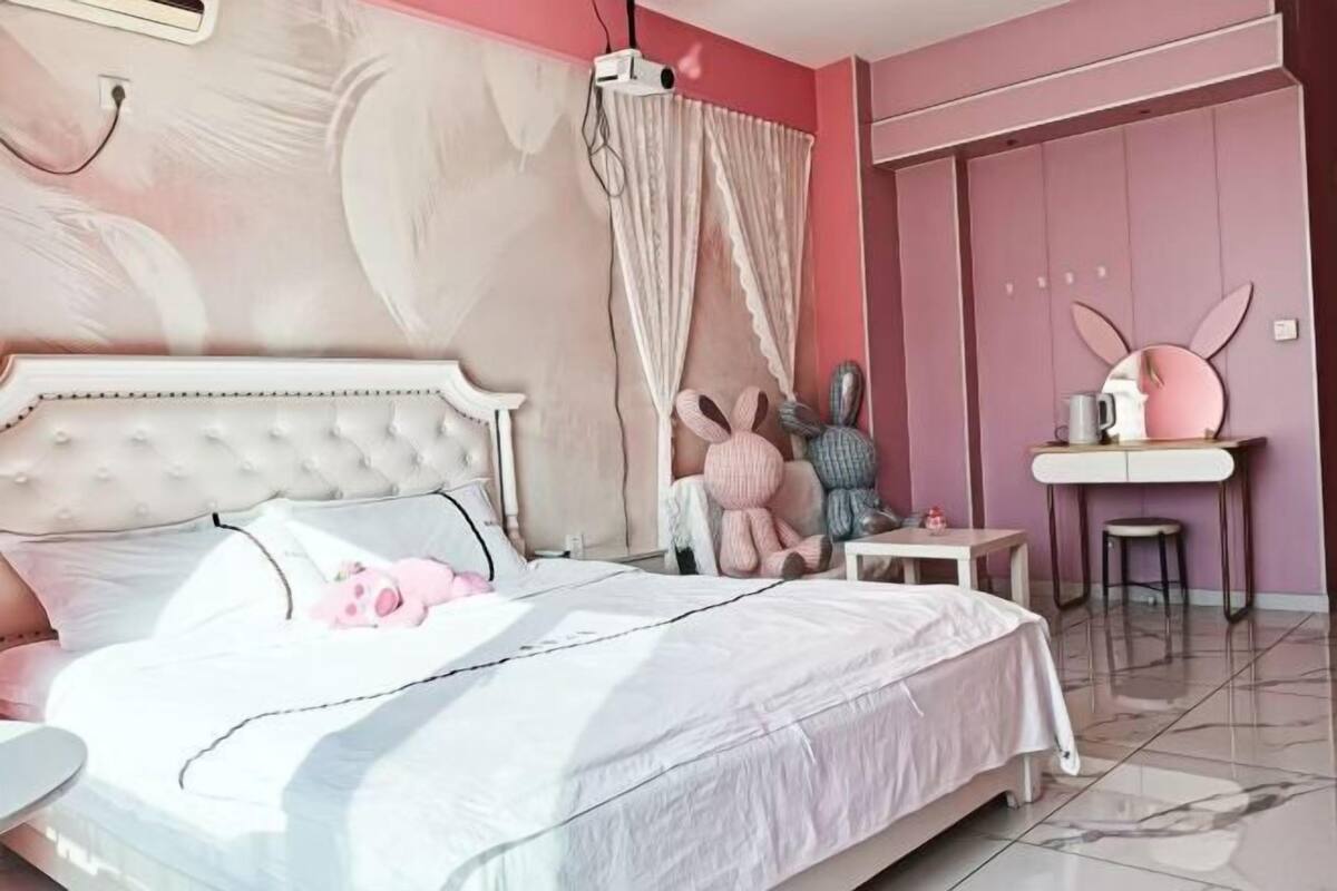 Un dormitorio con cama, tocador, silla y proyector instalado en la pared.
