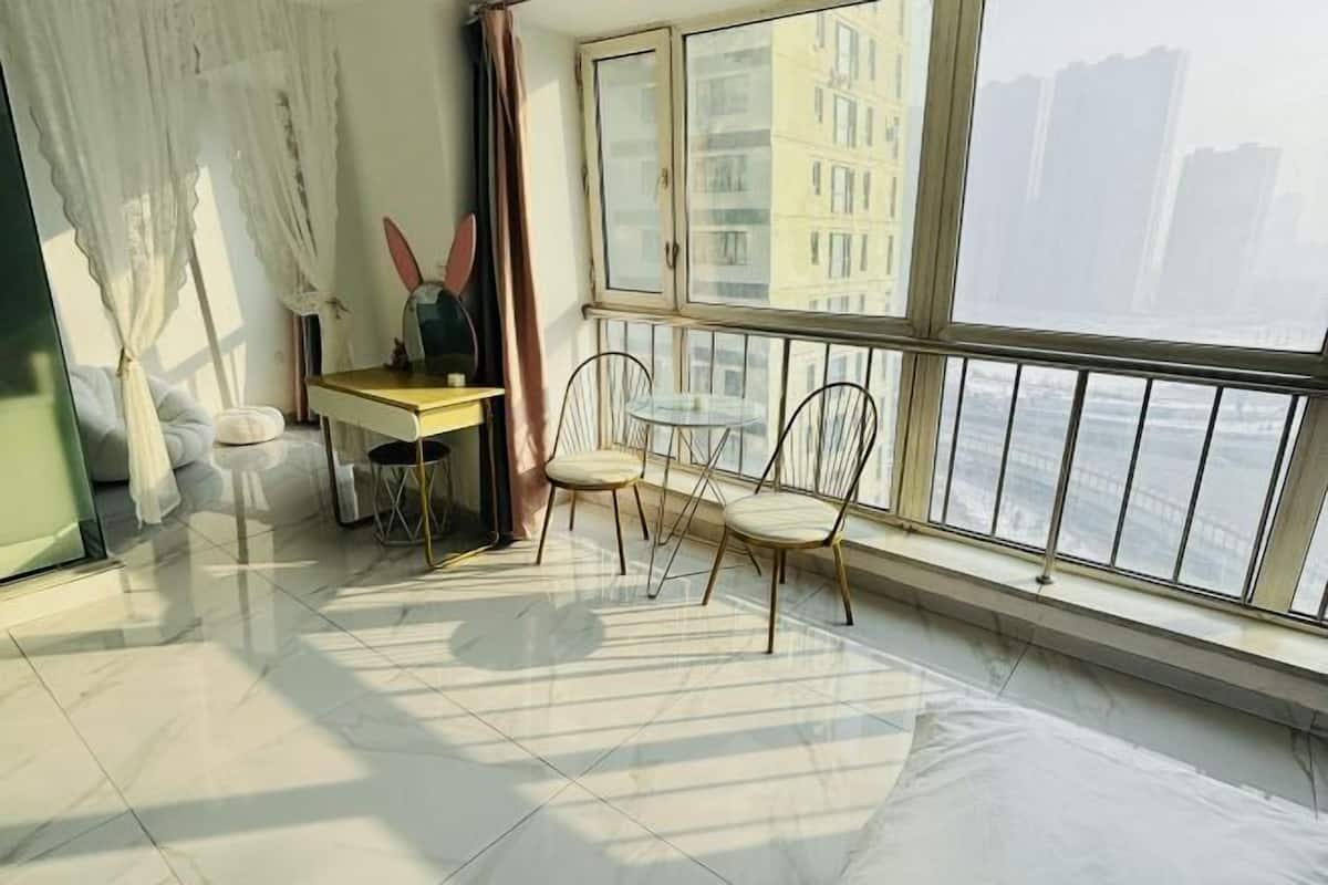 Una habitación con un ventanal grande, una mesa con sillas y vistas a edificios.