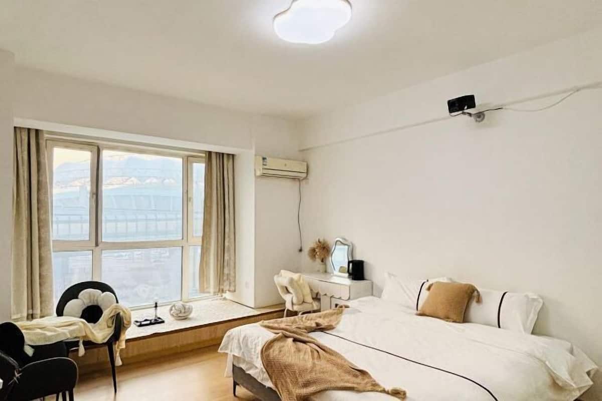 Un dormitorio con cama, escritorio, silla y ventana con vistas.