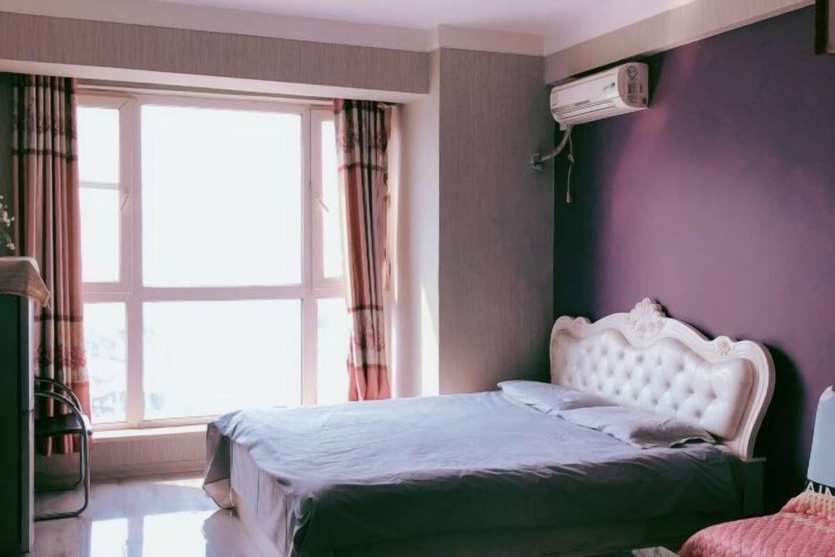 Un dormitorio con cama, aire acondicionado, ventana con cortinas y cómoda.