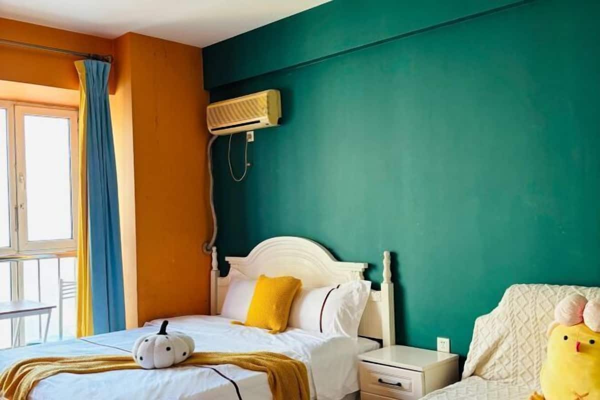 Un dormitorio con cama, mesita de noche, equipo de aire acondicionado y ventana con cortinas.