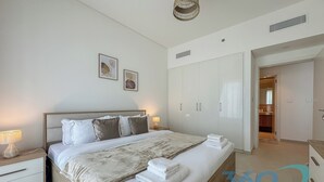 Une chambre à coucher comprenant un lit, des tables de chevet, une armoire et une porte donnant sur une autre pièce.