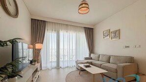 Un salon moderne avec un canapé, une table basse, un téléviseur et des rideaux.