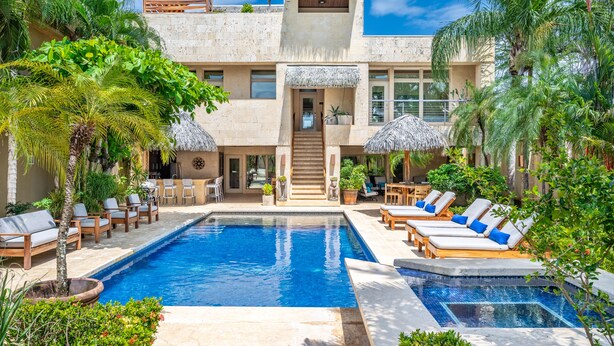 A pool area with lounge chairs and umbrellas, a staircase leading to a second floor, and a building with a modern design. - Private Luxurious Beachfront Villa with Chef, Household Staff, Concierge  (Potrero)