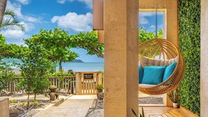 A wooden swing chair with blue cushions in a garden area with a view of the sea. - Private Luxurious Beachfront Villa with Chef, Household Staff, Concierge  (Potrero)