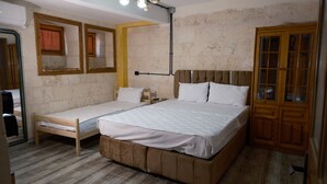 A room with two single beds and one double bed, wooden flooring, a brick wall, and a wooden wardrobe. - Ruken Hanım Konağı (Gaziantep)