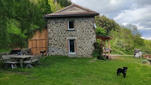 Una casa de piedra con techo de tejas, puerta de madera y un pequeño porche.