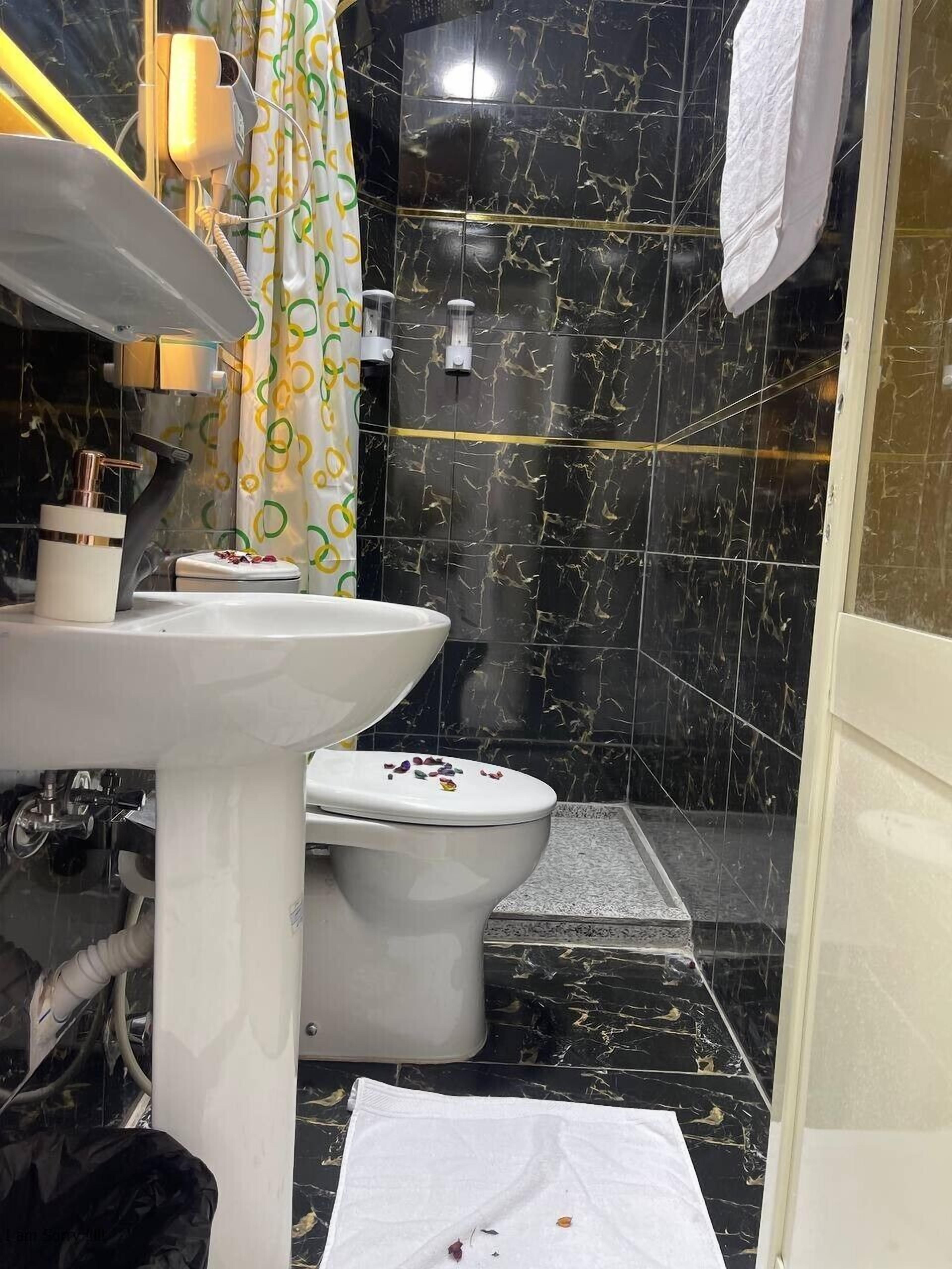 A bathroom with a white sink, toilet, and shower area.