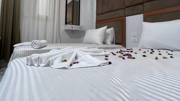 A hotel room with two beds, a large mirror, and a wall-mounted light fixture. - Future Hostel (Cairo)