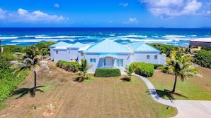 A beachfront property with a large house, a pool, and a view of the ocean. - Toes in the Sand | Beachfront Home & Private Pool (Christiansted)