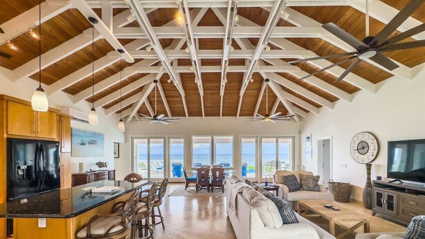 A spacious living area with a kitchen, dining area, and seating. - Toes in the Sand | Beachfront Home & Private Pool (Christiansted)